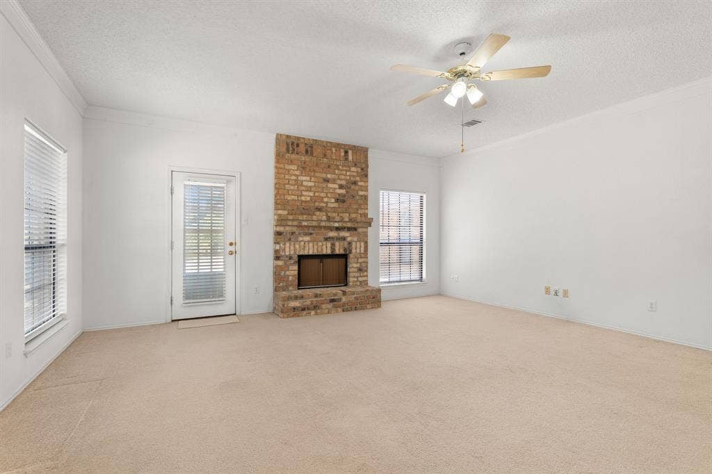 Brick-faced fireplace, large windows, ceiling fan, and crown molding