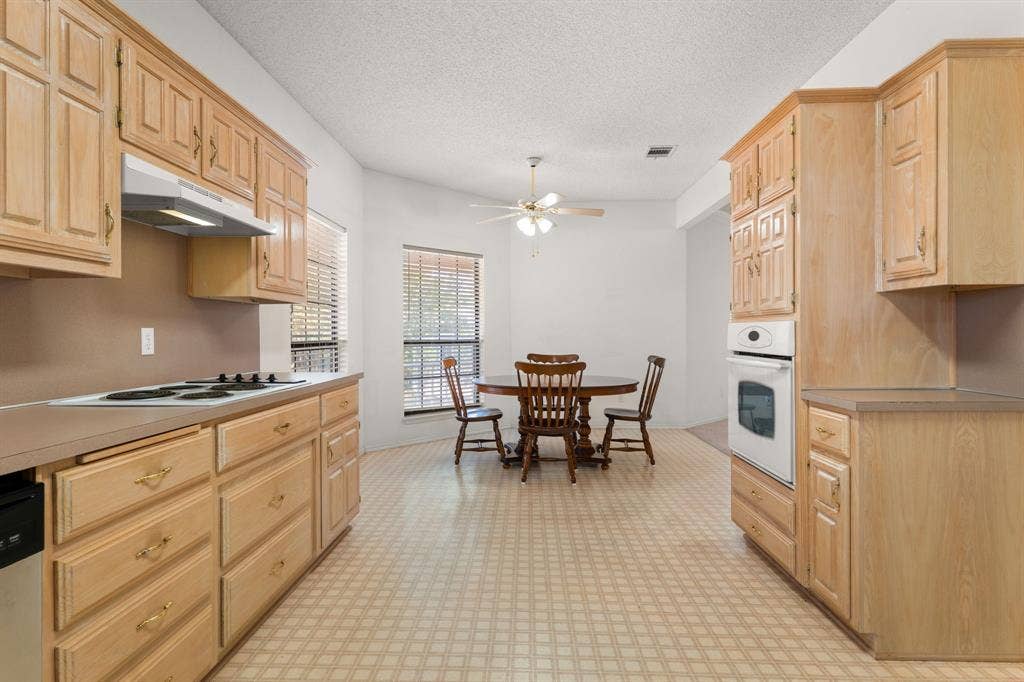 Kitchen with wood-finish cabinetry, built-in wall oven, and cooktop