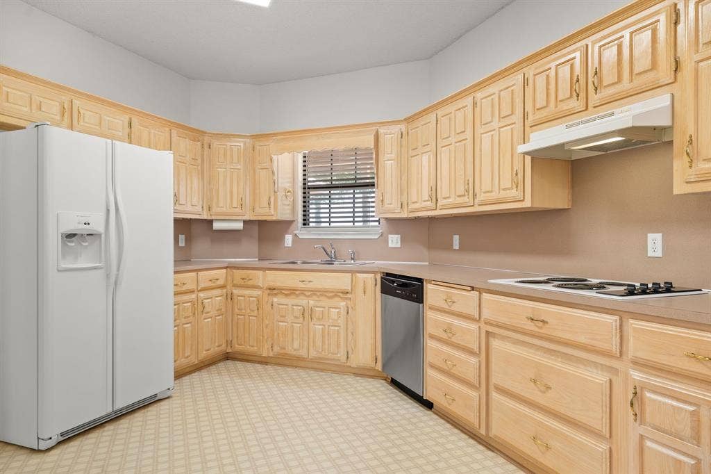Kitchen featuring light wood cabinetry, a built-in electric cooktop, stainless steel dishwasher, and a double basin sink