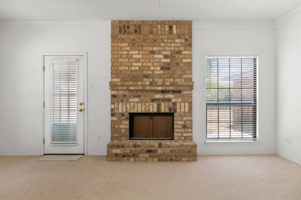 Brick fireplace with a metal firebox, adjacent to a glass-paned exterior door and a window