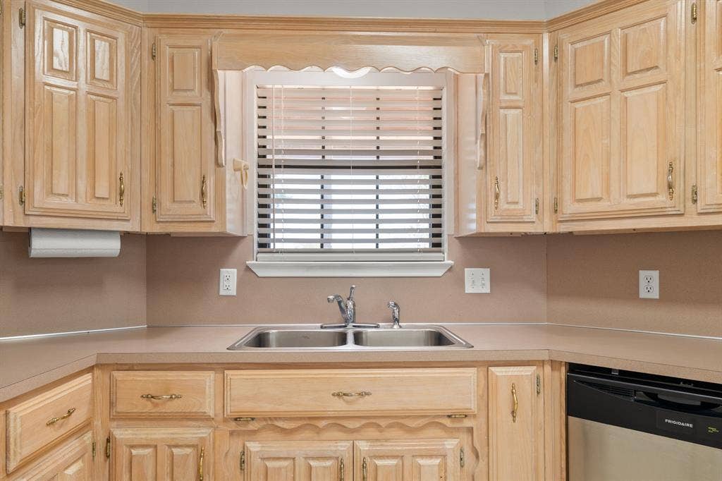 Kitchen featuring wood cabinetry, a double basin stainless steel sink, countertop space, and a built-in dishwasher