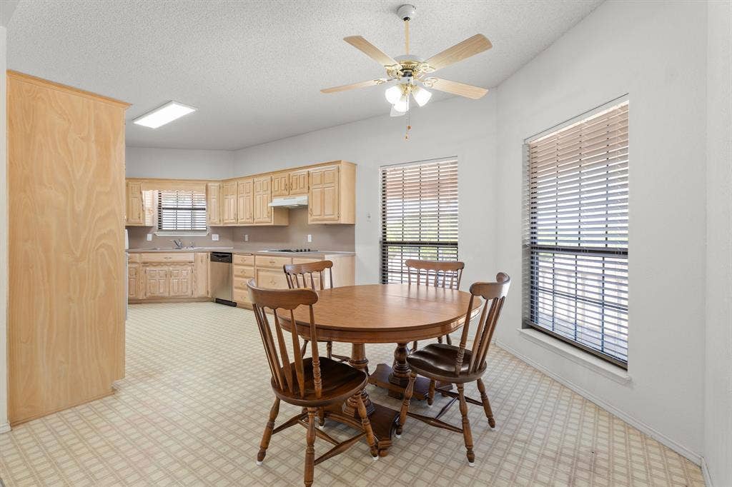 Kitchen with light wood cabinetry, stainless steel dishwasher, and patterned flooring