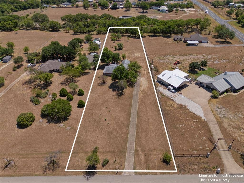 Expansive land parcel featuring a paved driveway, mature trees, and natural landscaping