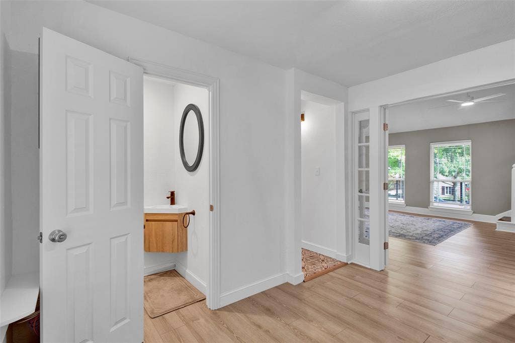 Light wood-finish flooring throughout, white interior doors, and white walls
