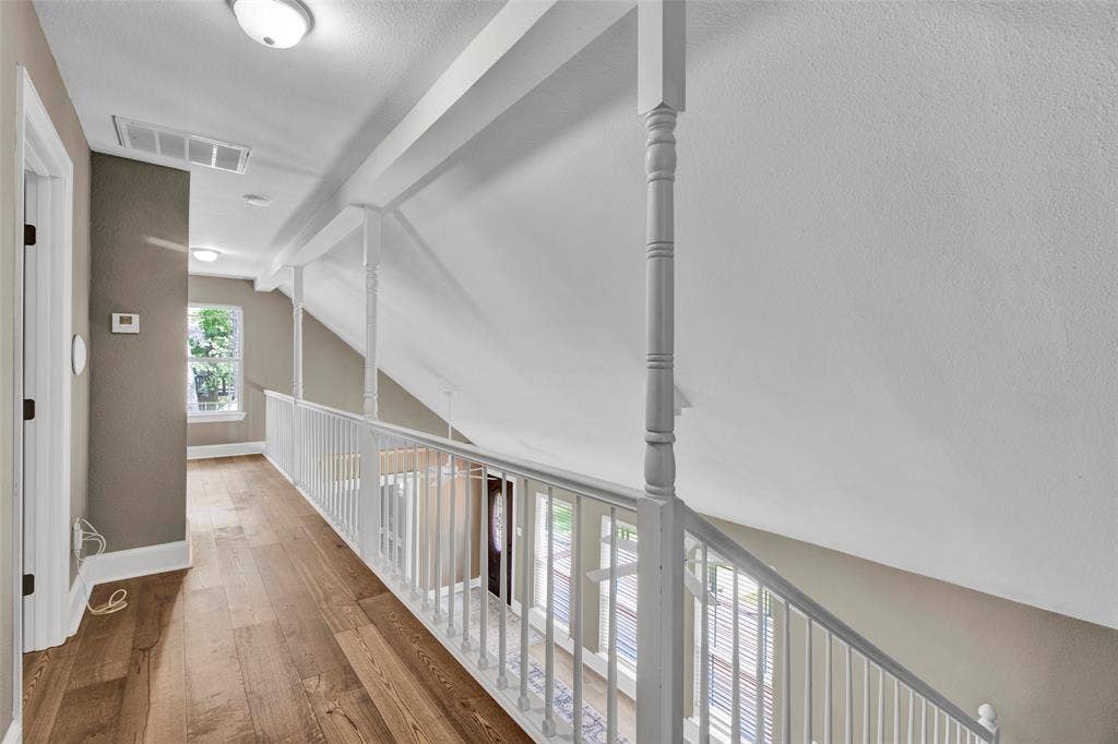 Wood-finish flooring, white spindle railing, and recessed lighting