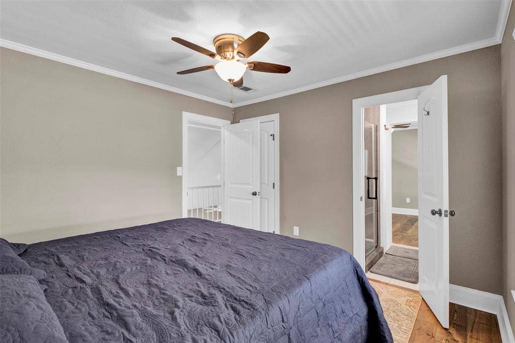 Ceiling fan with integrated lighting, crown molding, white trim, wood-finish flooring, and a glass-enclosed shower