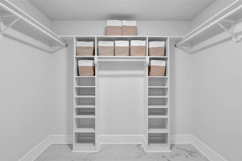 Built-in white shelving system featuring multiple storage compartments and hanging rods