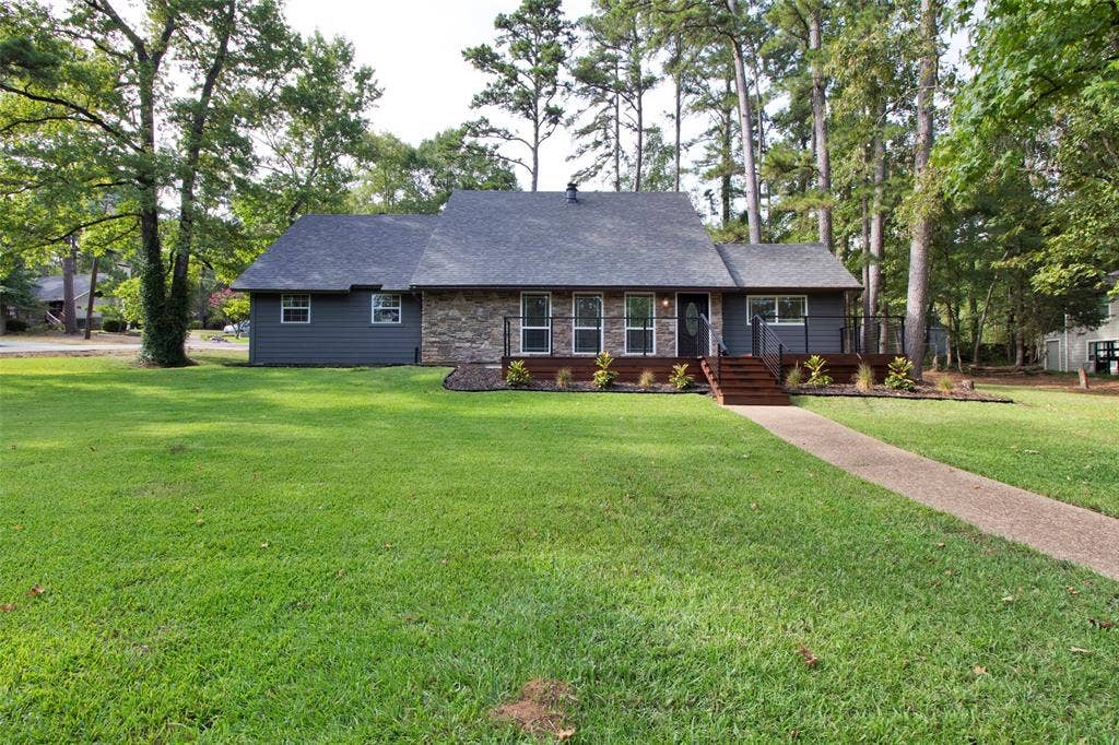Exterior featuring a stone facade, dark siding, dark shingle roof, and a wood deck