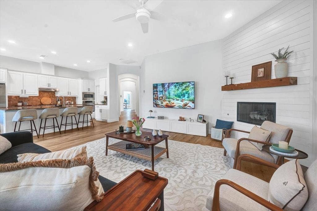 Open-concept living space featuring wood-finish flooring, a contemporary ceiling fan, and recessed lighting