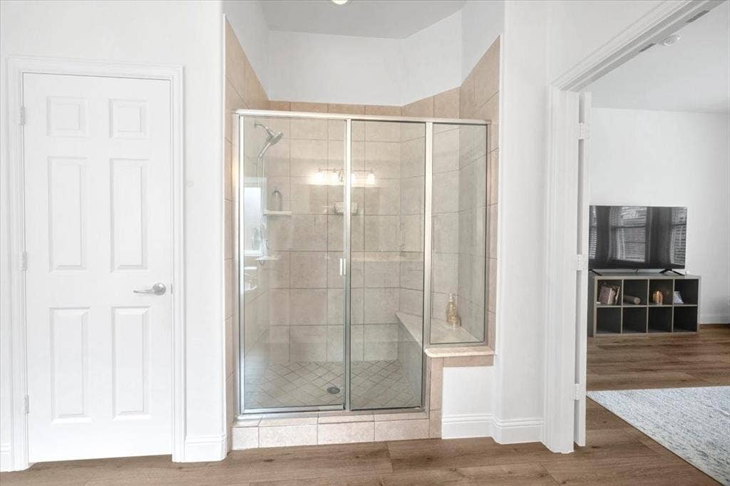 Glass-enclosed shower with a built-in bench, tiled walls, and a recessed light fixture