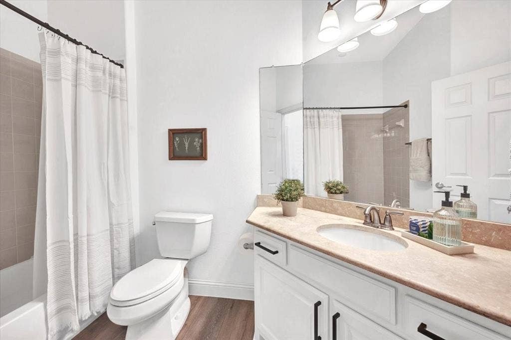 White vanity with dark hardware, undermount sink, and a stone-finish countertop