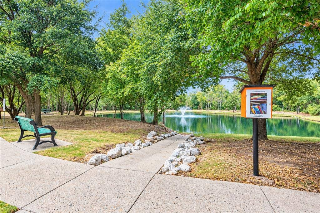 Concrete pathway with rock border, mature trees, and a park bench