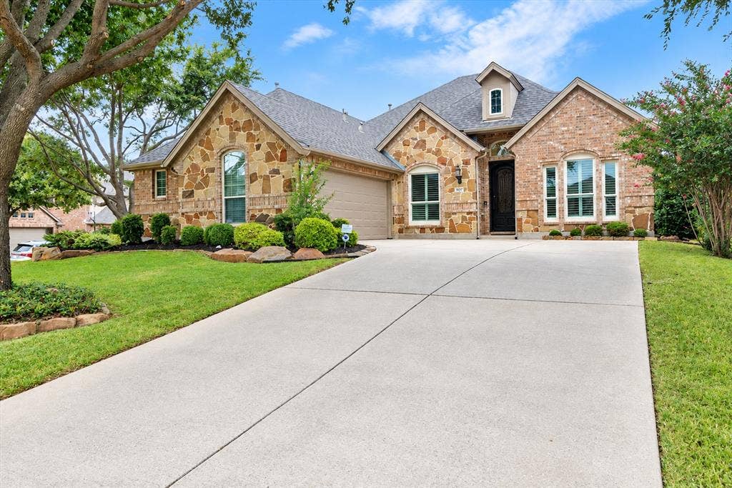 Stone and brick facade with an integrated garage, dormer window, and an arched entry