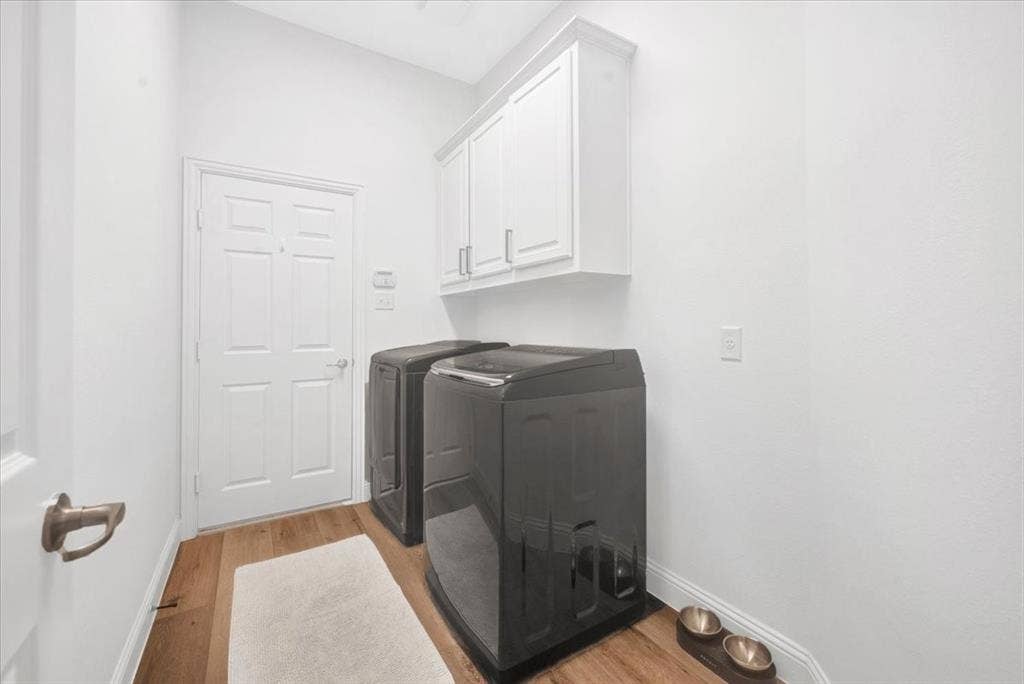 Wood-finish flooring with white baseboards, white painted walls, and white upper cabinetry