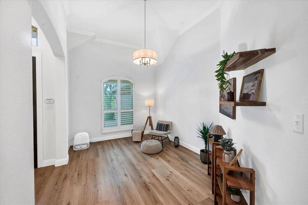 Vaulted ceiling with an arched window, wood-finish flooring, and a contemporary drum pendant light