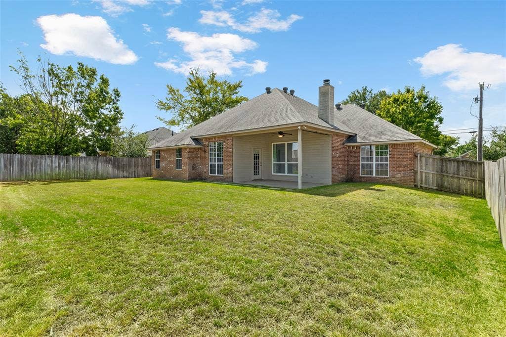 11848 County Road 167, Tyler, TX 75703 Expansive green yard with perimeter fencing and a covered patio featuring an outdoor ceiling fan