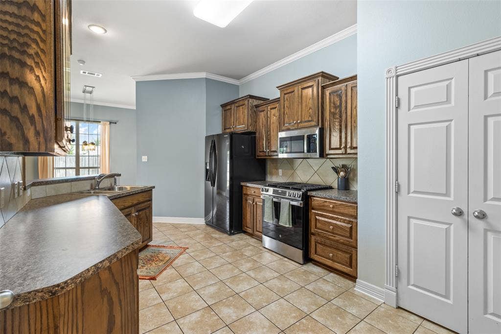 11848 County Road 167, Tyler, TX 75703 Kitchen featuring wood-finish cabinetry, tile flooring, and integrated black appliances