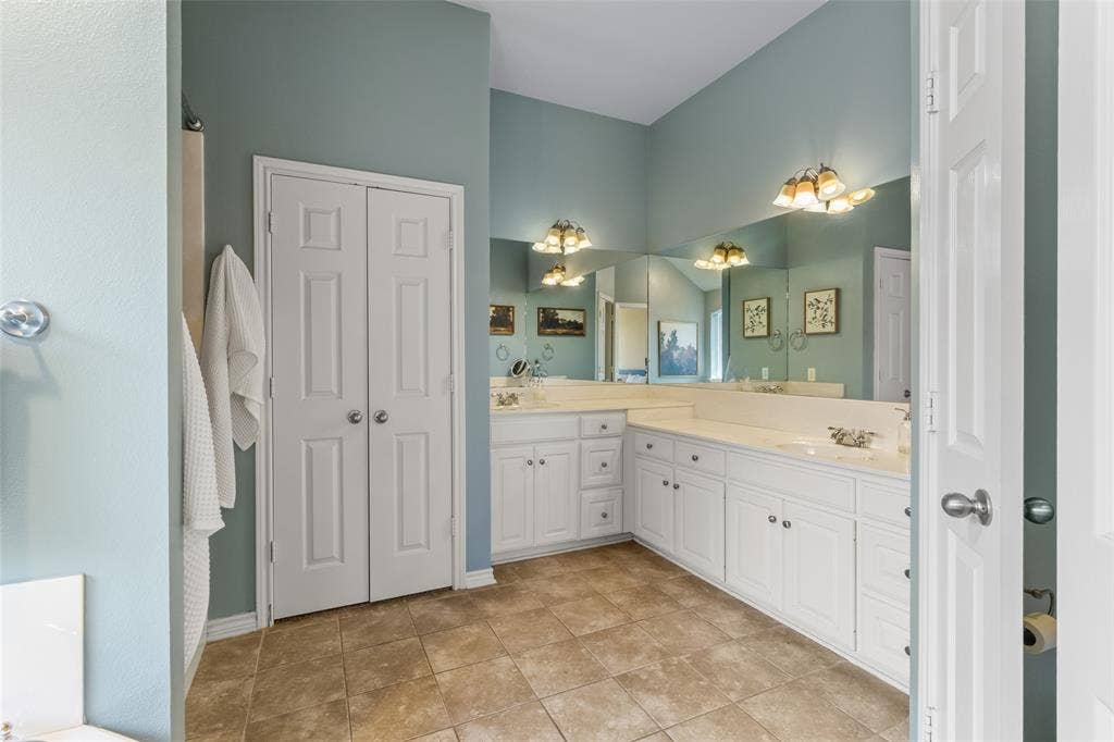 11848 County Road 167, Tyler, TX 75703 Dual vanity with integrated sinks, extensive counter space, white cabinetry, tiled flooring, and vaulted ceiling
