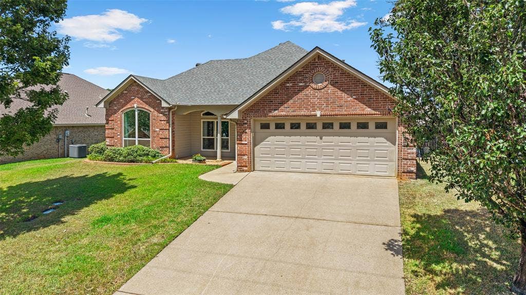 11848 County Road 167, Tyler, TX 75703 Brick and siding exterior with an arched window, a two-car garage, a concrete driveway, and a shingle roof