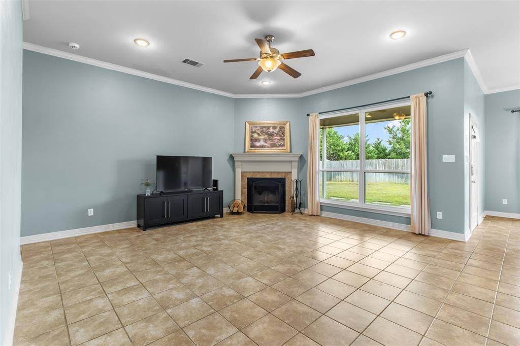 11848 County Road 167, Tyler, TX 75703 Tiled flooring, corner fireplace with mantel, ceiling fan with integrated lighting, recessed lighting, and a large window overlooking the backyard