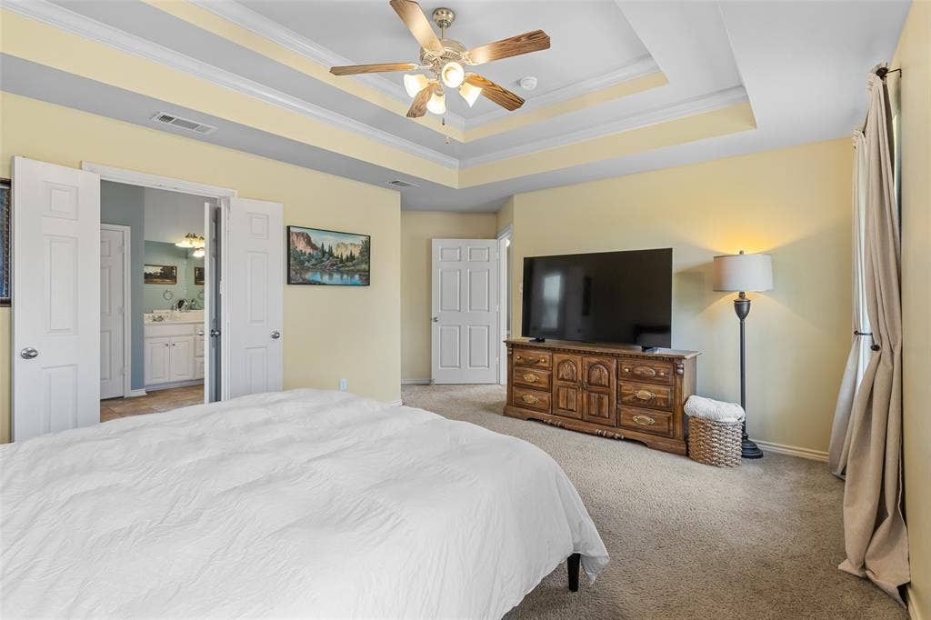 11848 County Road 167, Tyler, TX 75703 Spacious master suite featuring a tray ceiling with ceiling fan, soft yellow walls, and neutral carpeting