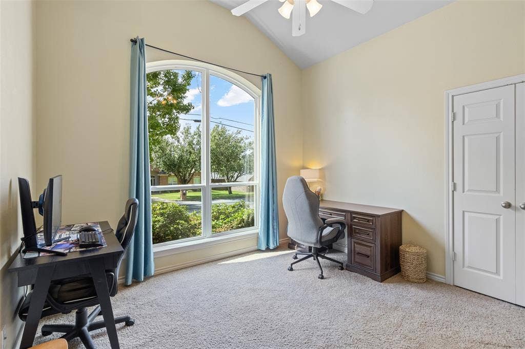 11848 County Road 167, Tyler, TX 75703 Bright, naturally lit home office featuring expansive glass French doors framed in blue, gleaming wood-finish desk with integrated storage, ergonomic office seating, neutral carpet flooring, and a modern ceiling fan
