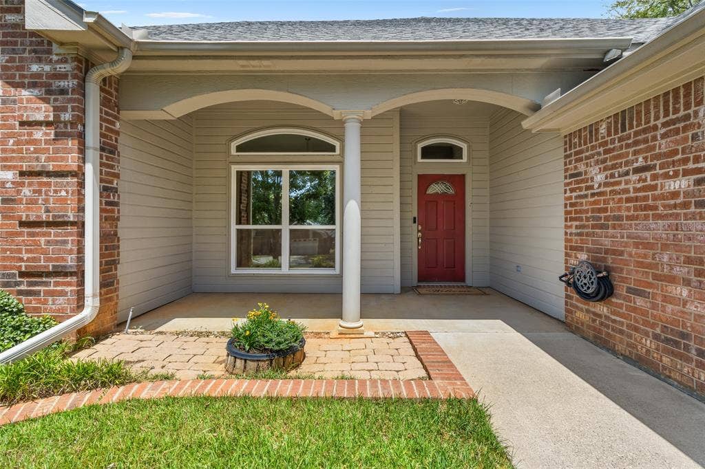 11848 County Road 167, Tyler, TX 75703 Brick exterior facade with a covered entry, decorative arched window, and a red paneled entry door with an arched transom