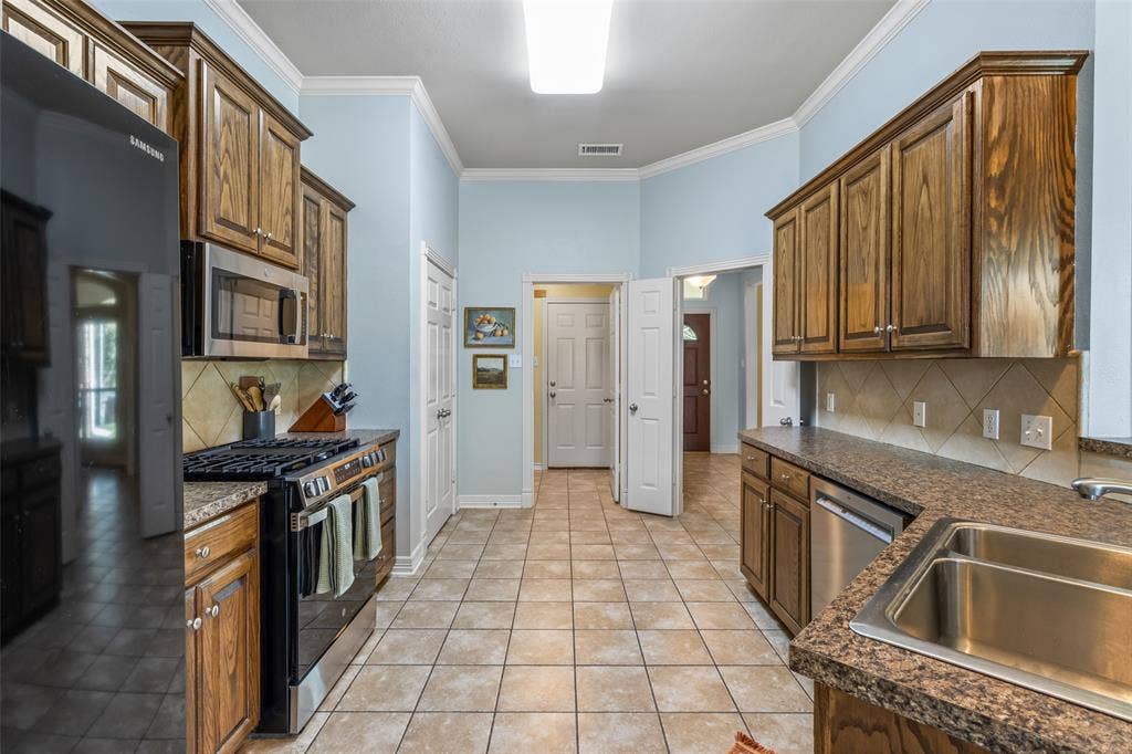 11848 County Road 167, Tyler, TX 75703 Tile flooring, wood-finish cabinetry, stainless steel appliances, granite-style countertops, and a tile backsplash