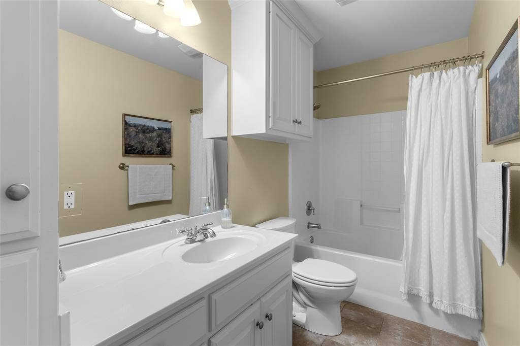 11848 County Road 167, Tyler, TX 75703 White vanity with an integrated sink and chrome faucet, large vanity mirror, white built-in cabinetry, and a white bathtub with a shower