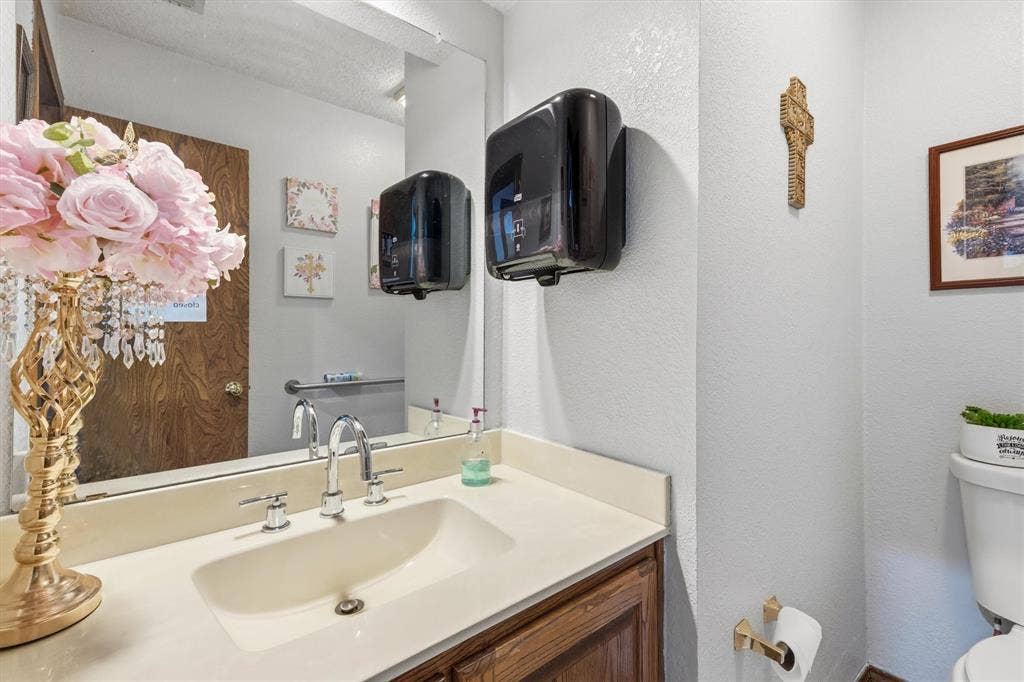 1055 W Pioneer Parkway, Grand Prairie, TX 75051 Vanity with an integrated sink, chrome faucet, and wood-finish cabinetry