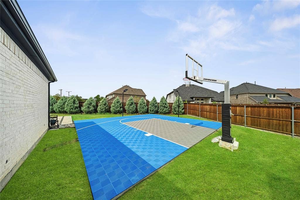 467 Mayfair Lane, Frisco, TX 75033 Expansive backyard featuring a full basketball court with blue and gray surfacing, a built-in basketball hoop, and a perimeter of manicured lawn