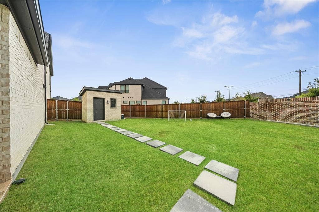 467 Mayfair Lane, Frisco, TX 75033 Expansive backyard featuring a manicured lawn, wood fencing, and a detached shed with a sloped roof