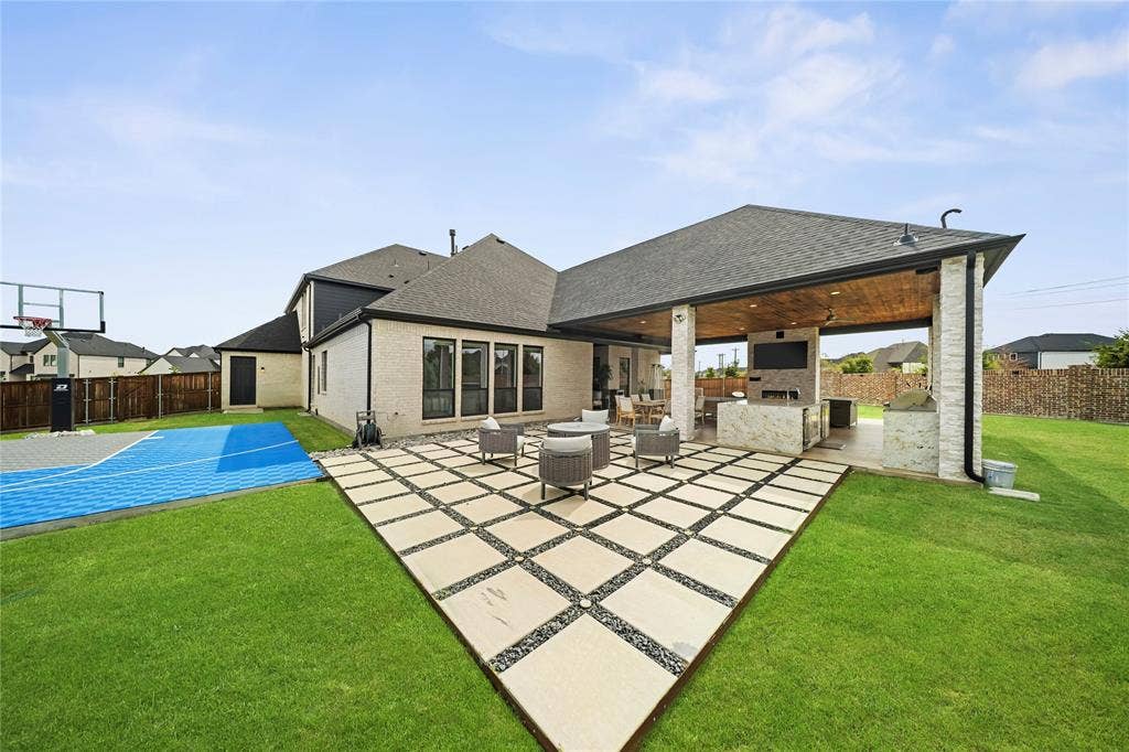 467 Mayfair Lane, Frisco, TX 75033 Expansive outdoor entertaining area featuring a covered patio with a built-in outdoor kitchen, stone-clad columns, a decorative wood ceiling, and a paver patio with a gravel inlay