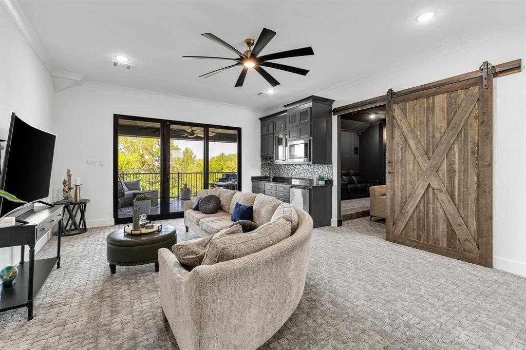 1561 Saint Peter, Prosper, TX 75078 Recessed lighting, ceiling fan, built-in wet bar with mosaic tile backsplash, wood barn door, and glass sliding doors to an outdoor area