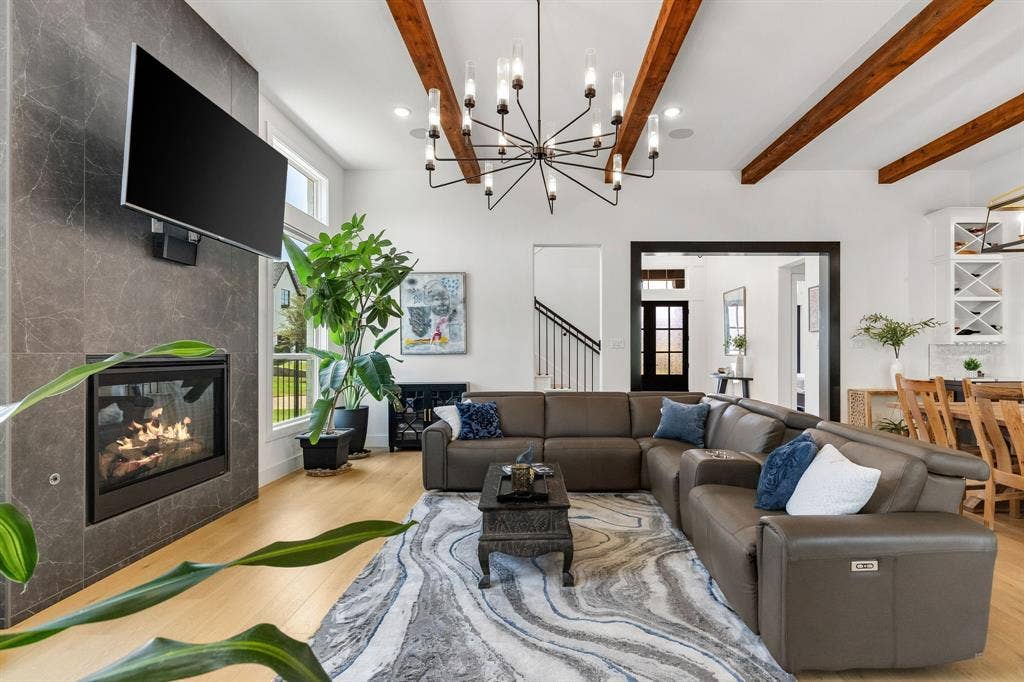 1561 Saint Peter, Prosper, TX 75078 Open-concept living room featuring a curved sectional sofa arrangement, wood-finish flooring, and a geometric area rug