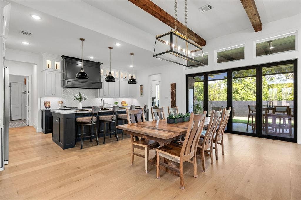 1561 Saint Peter, Prosper, TX 75078 Spacious open-concept layout with wood-finish flooring, vaulted ceilings with exposed beams, and a kitchen island with seating
