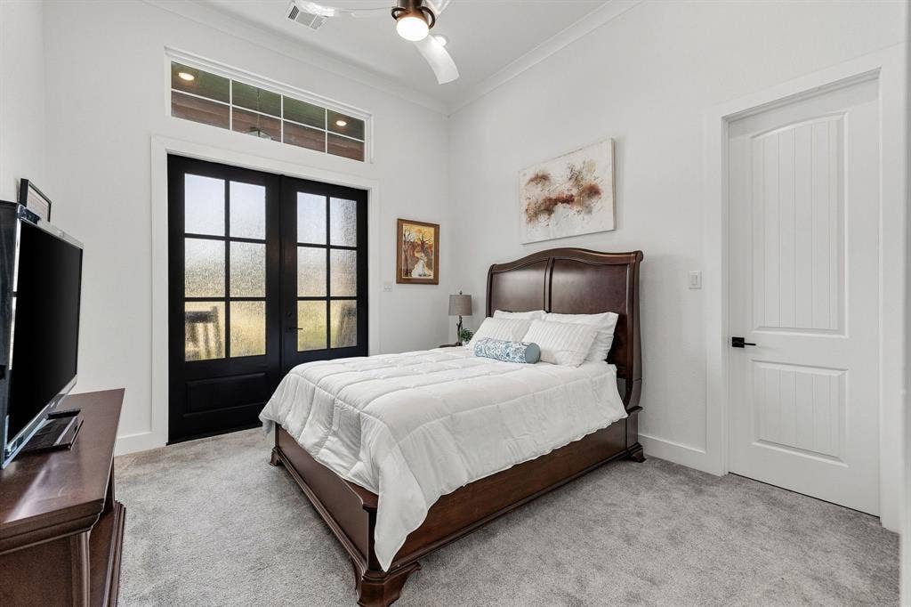 1561 Saint Peter, Prosper, TX 75078 Spacious secondary bedroom featuring a wood-finish bed frame, soft-gray carpeting, and abundant natural light from French doors