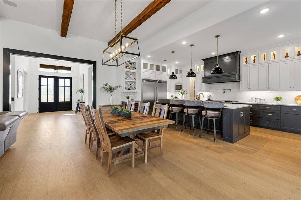 1561 Saint Peter, Prosper, TX 75078 Vaulted ceilings with exposed wood beams, light wood-finish flooring, two-tone cabinetry, kitchen island with seating, and a decorative ceiling light fixture
