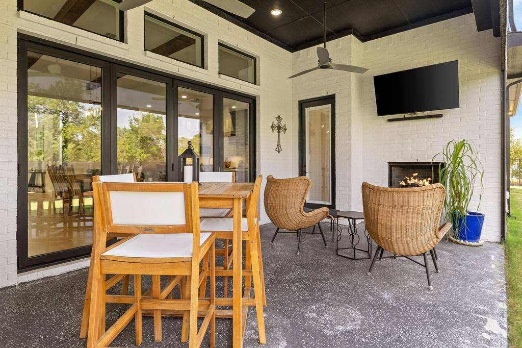 1561 Saint Peter, Prosper, TX 75078 Covered patio featuring a ceiling fan, a mounted television, a fireplace, and a large sliding glass door