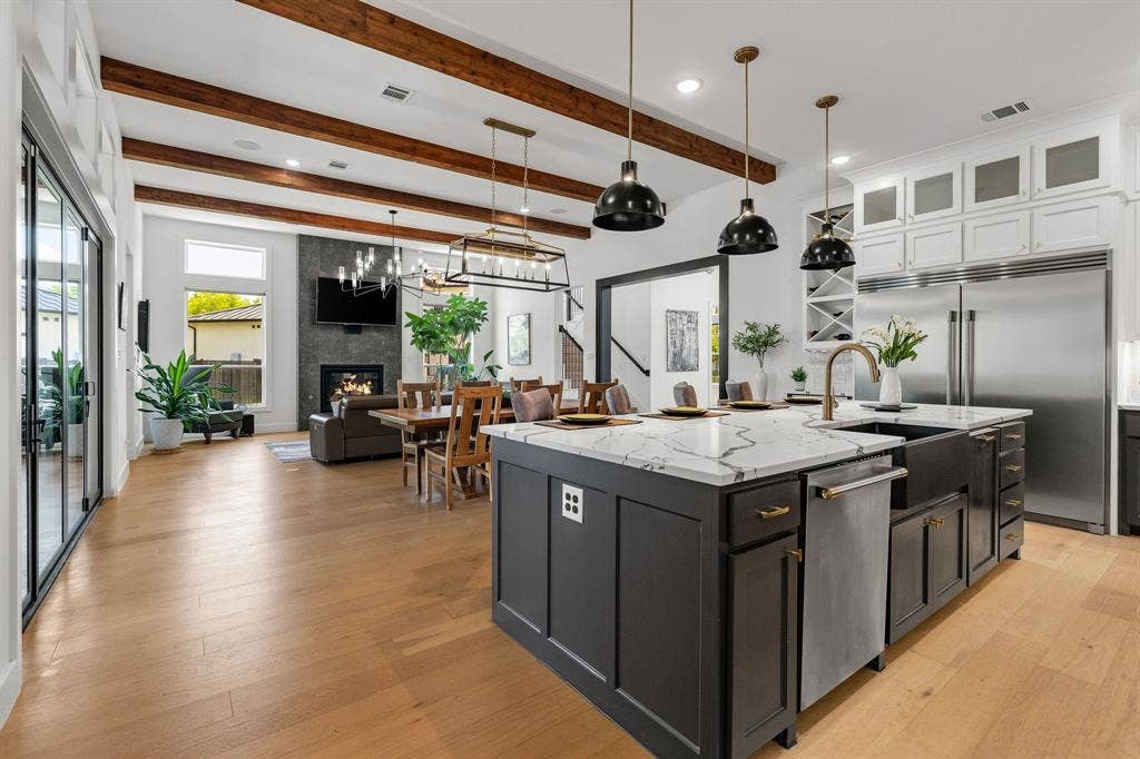 1561 Saint Peter, Prosper, TX 75078 Open concept living space featuring wood-finish flooring, exposed ceiling beams, and a modern kitchen island with a farmhouse sink