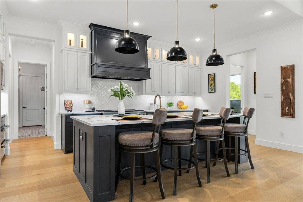 1561 Saint Peter, Prosper, TX 75078 Kitchen featuring a central island with countertop seating, white upper cabinetry, dark lower cabinetry, and wood-finish flooring