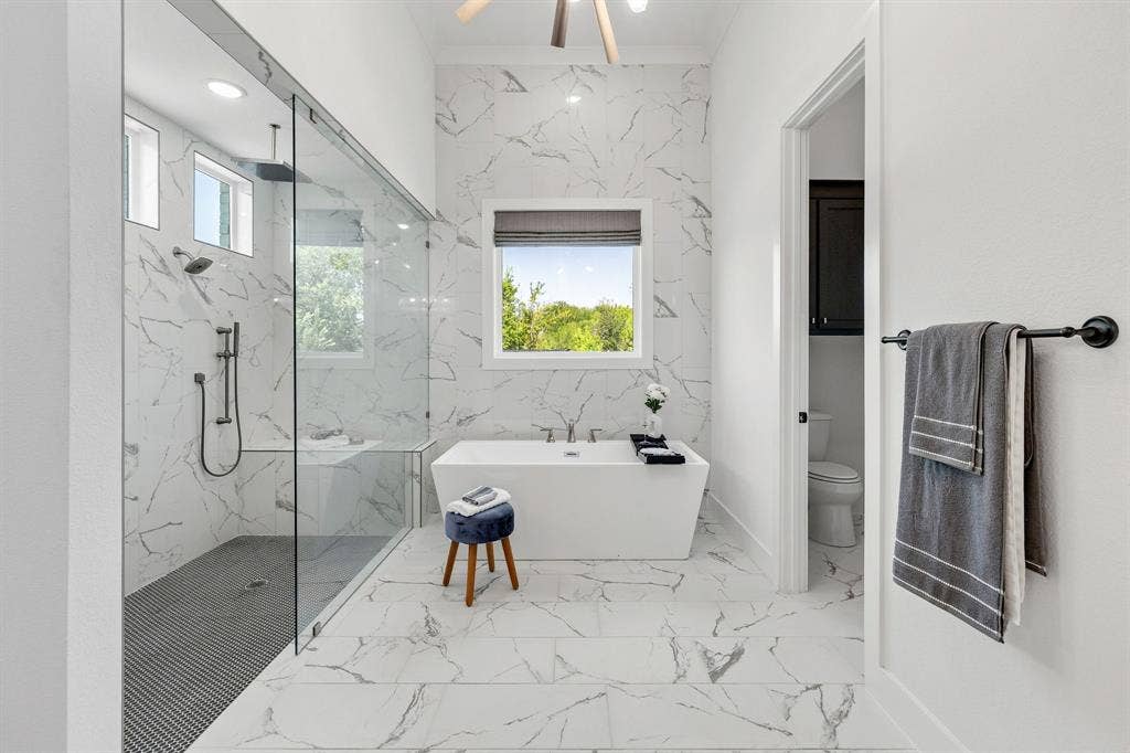 1561 Saint Peter, Prosper, TX 75078 Spacious bathroom featuring a freestanding tub, large walk-in shower with glass enclosure, dual shower heads, and white marble-look tile flooring and walls