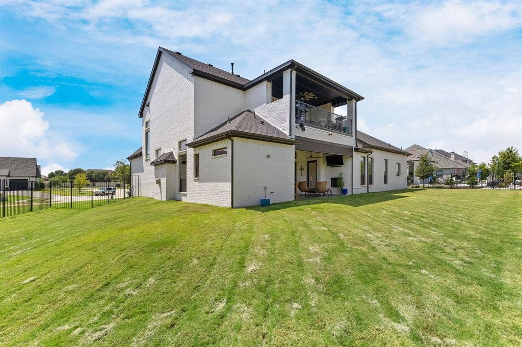 1561 Saint Peter, Prosper, TX 75078 Two-story exterior with white brick, a covered second-story balcony with glass railing, and an expansive backyard