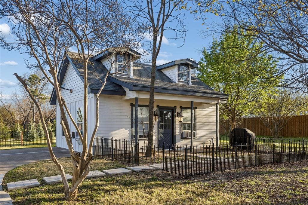 3706 Castle Drive, Rowlett, TX 75089 White siding exterior with a dark-trimmed gable roof, prominent dormer windows, a covered entry, and a dark front door
