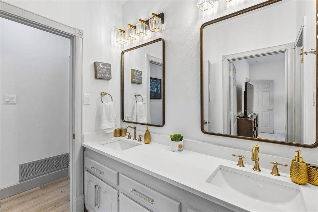3706 Castle Drive, Rowlett, TX 75089 Dual vanity with integrated sinks and white countertops, complemented by gold-finish fixtures and framed mirrors