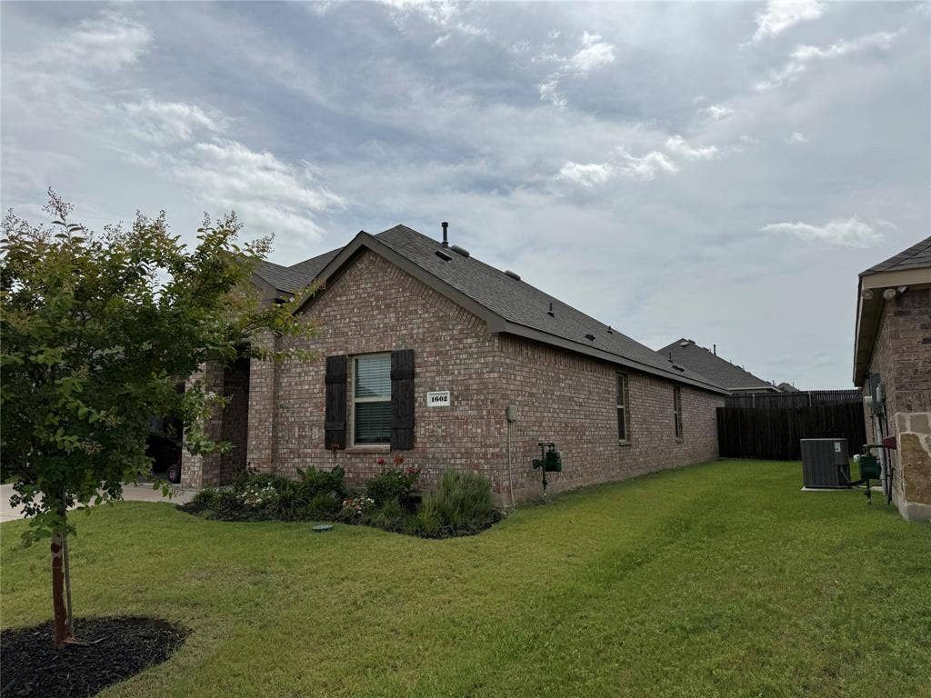 1602 Maple Ridge Drive, Princeton, TX 75407 Brick exterior with dark shutters, gabled roofline, and attached fencing