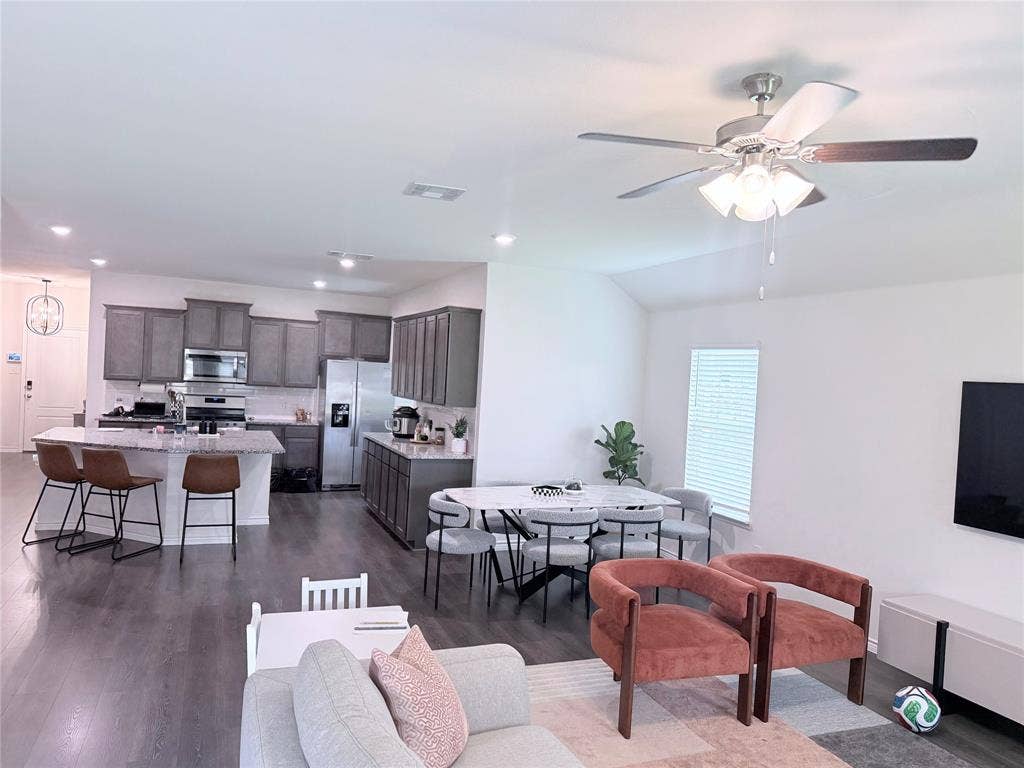 1602 Maple Ridge Drive, Princeton, TX 75407 Open-concept living space featuring wood-finish flooring, vaulted ceilings, and a ceiling fan with integrated lighting
