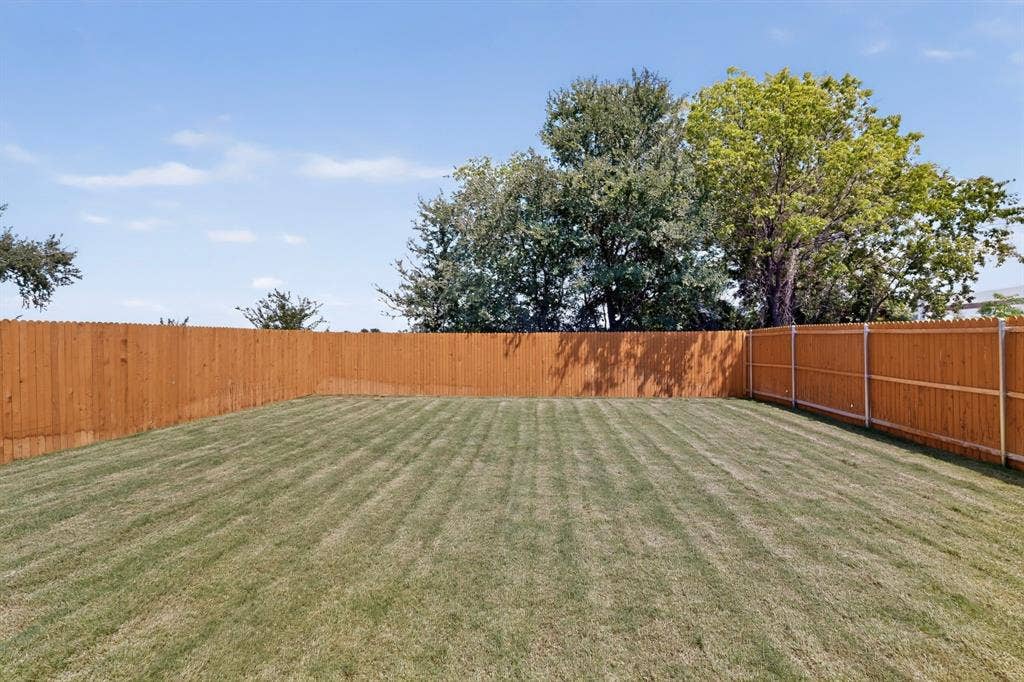 624 Kinglet Lane, Princeton, TX 75407 Expansive backyard featuring a manicured lawn, a full wood privacy fence, and mature trees