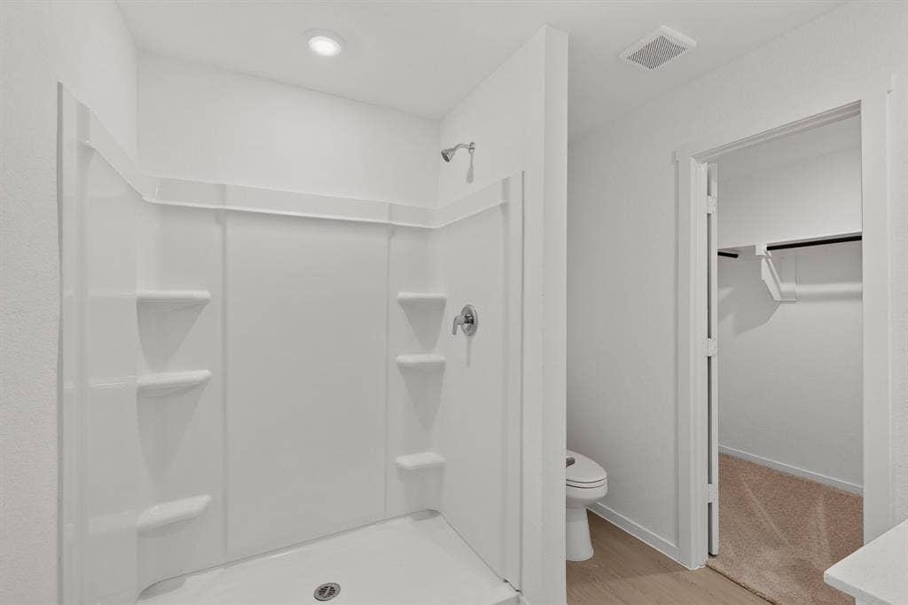624 Kinglet Lane, Princeton, TX 75407 White shower enclosure with built-in shelving, chrome fixtures, and a recessed ceiling light