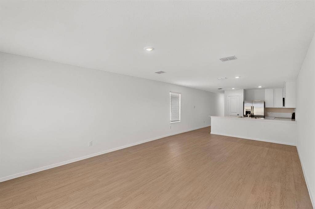 624 Kinglet Lane, Princeton, TX 75407 Open-concept living area featuring wood-finish flooring, recessed lighting, and a kitchen with white cabinetry and stainless steel appliances